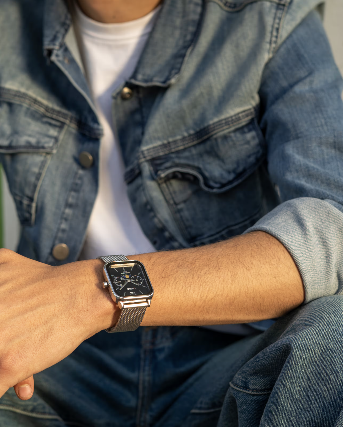 Image of a square metal watch on the hand of a model