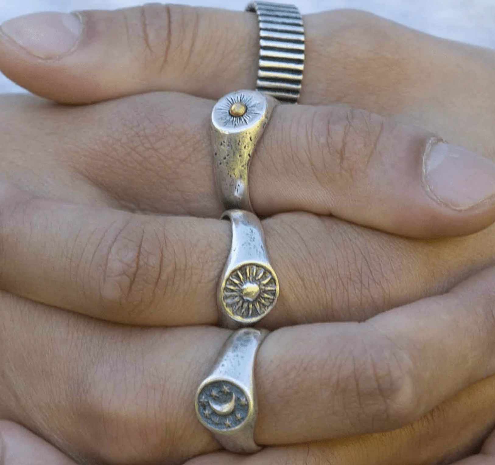 A signet ring with a sun on it on a hand